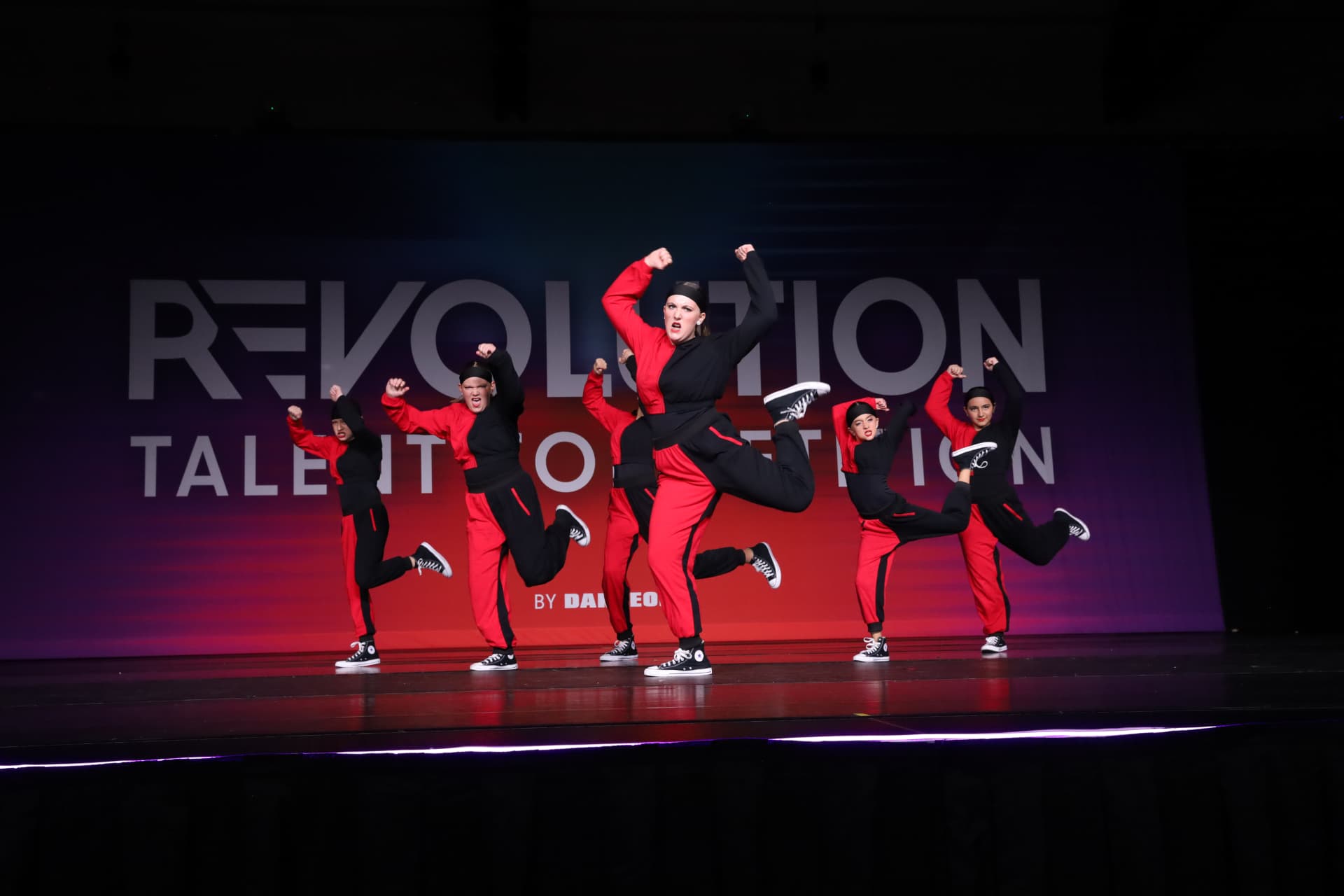 MSDC dancers jumping together in red and black costumes on stage